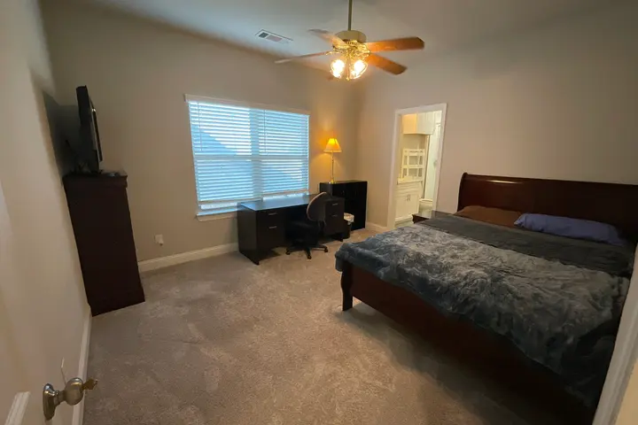 Queen bed, desk under the window, and the private bathroom doorway