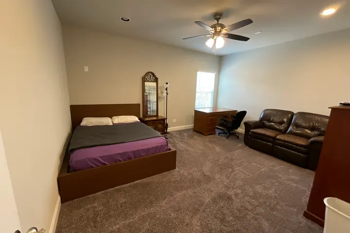 Large room with a queen bed, mirror, desk, and leather sofa