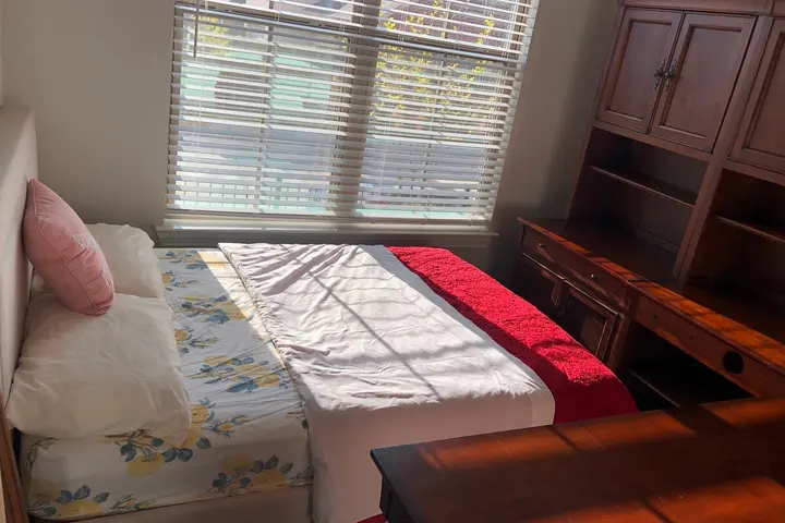 Bed with wooden headboard by the window