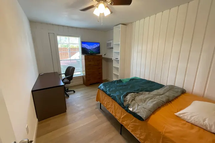 Bedroom with desk and wall-mounted TV